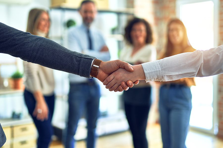 About Our Agency - Group of Business Workers Standing Together and Shaking Hands at the Office